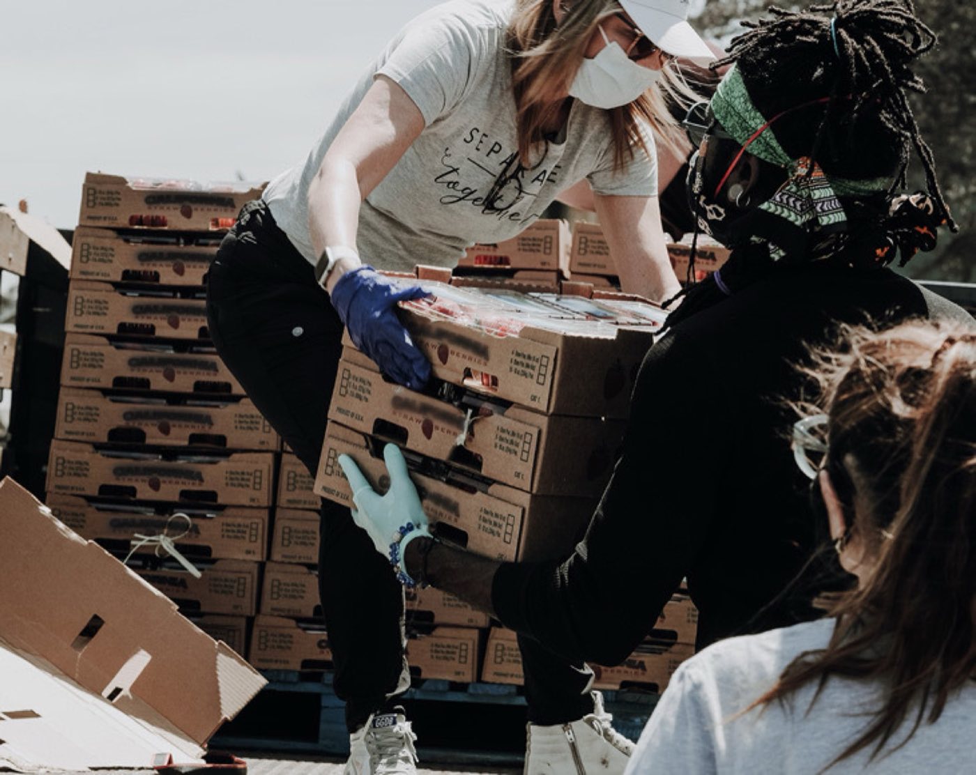 Volunteers handing off boxes of food at a community distribution